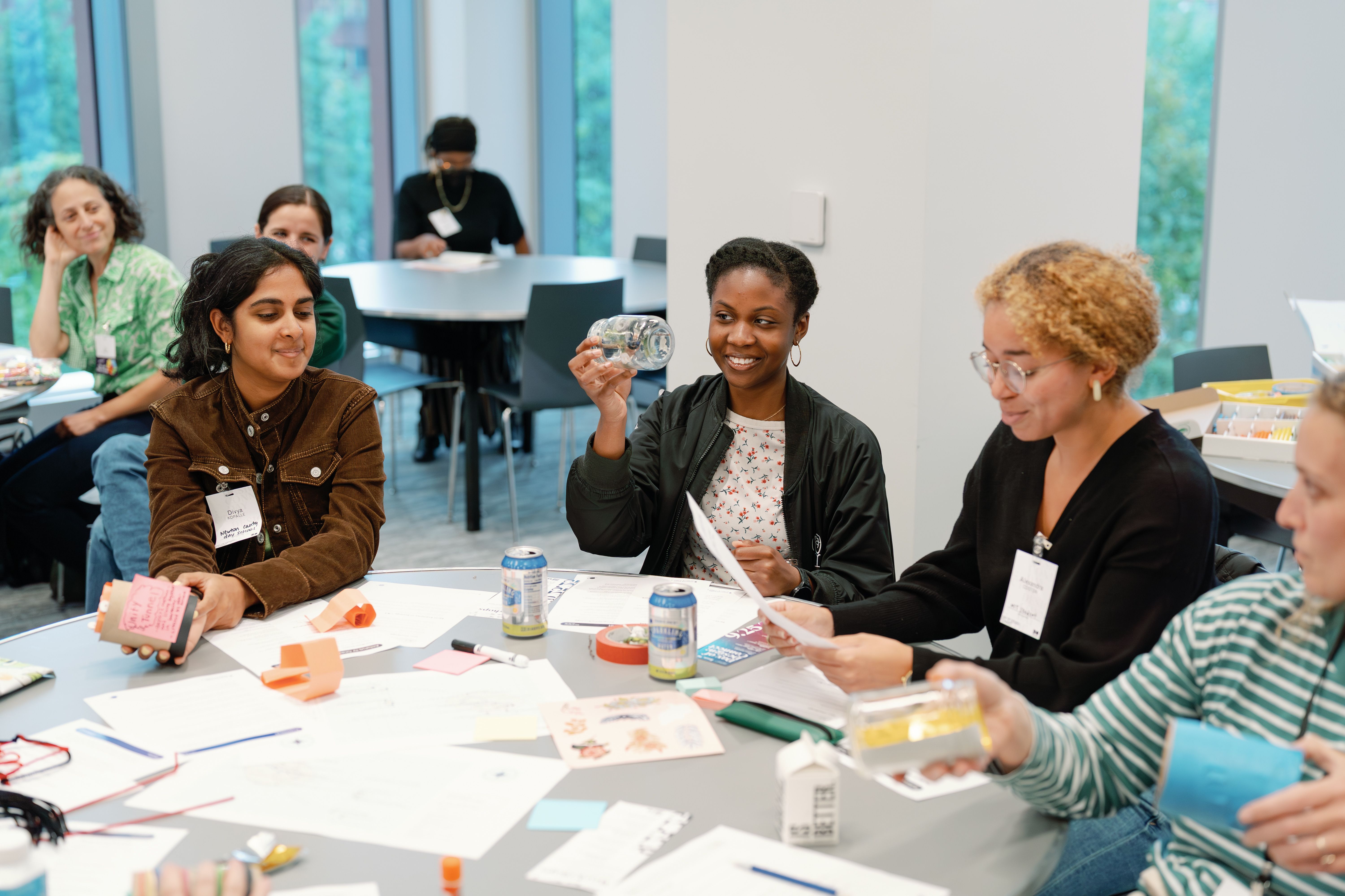 An educator holds up a water bottle, smiling, while an other reviews their instructions.
